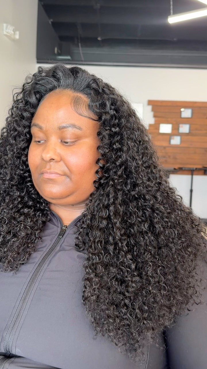 Person displaying long layered dark curls with shorter face-framing curls indoors