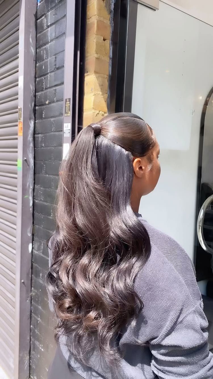 Long dark curls worn half-up in a small crown ponytail