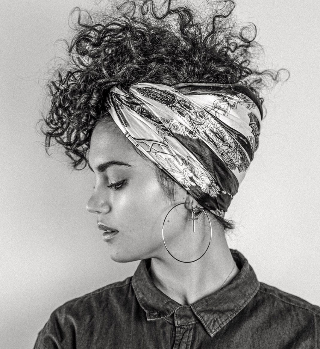 Woman wearing a patterned headscarf over voluminous curly hair