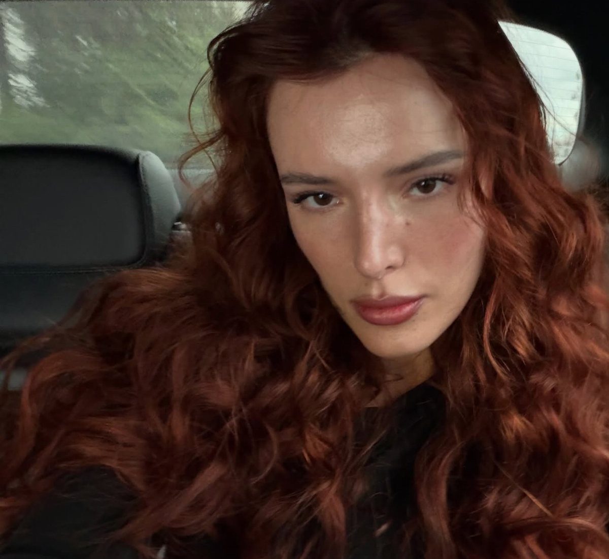Woman with long auburn curls sitting in a car