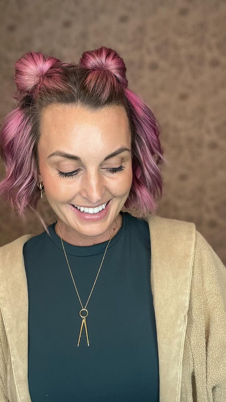 Woman with pink hair wearing two small knots beside a center part