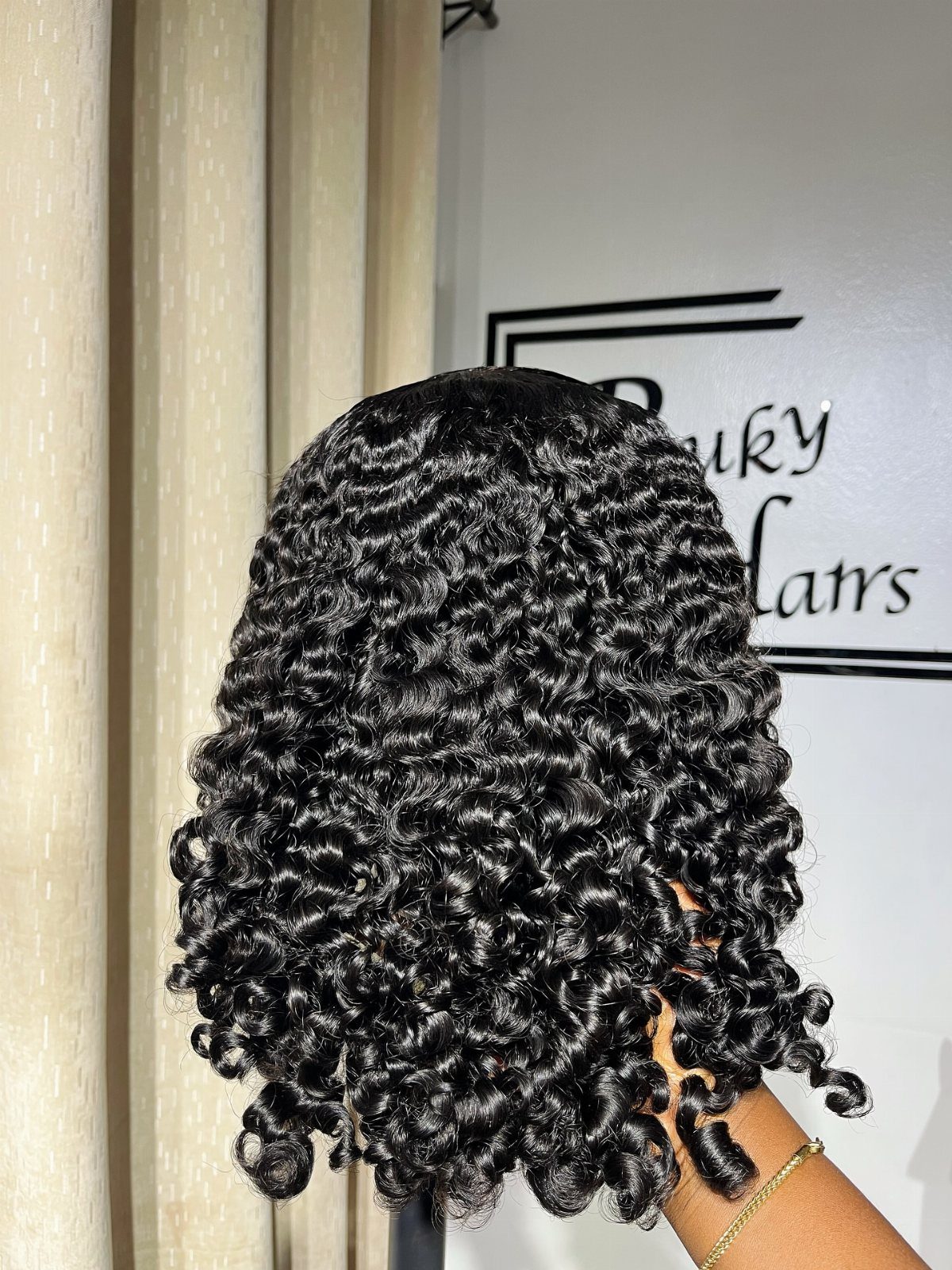 Defined black ringlet curls cover the back of a person's head