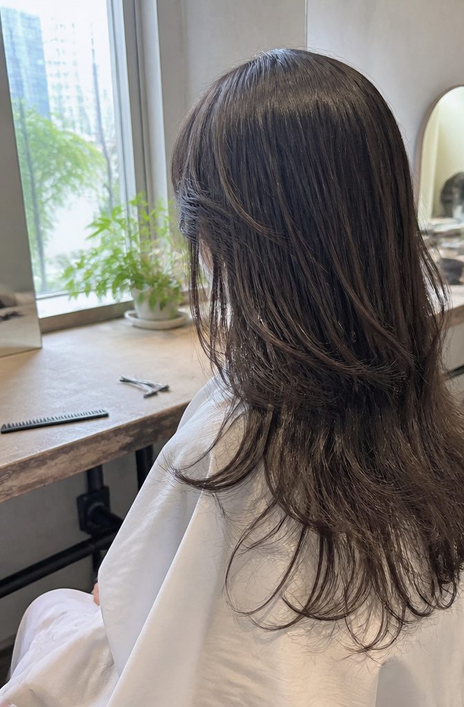 Long hair with wispy bangs and face-framing layers at the temples