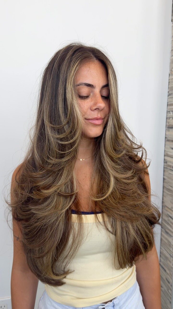 Woman showing voluminous long brown hair with subtle layered waves and face-framing highlights
