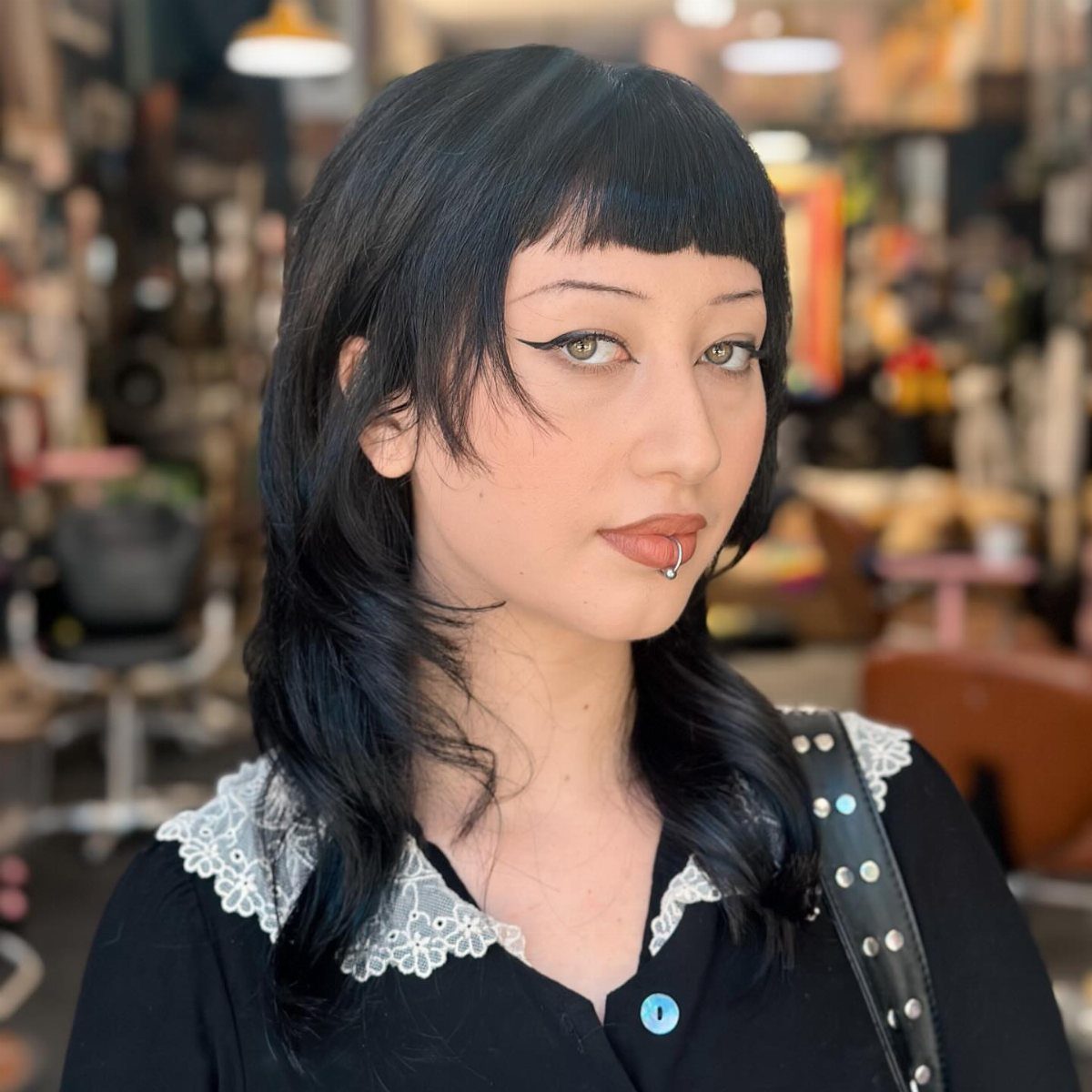 Person with long black layered hair and straight blunt bangs