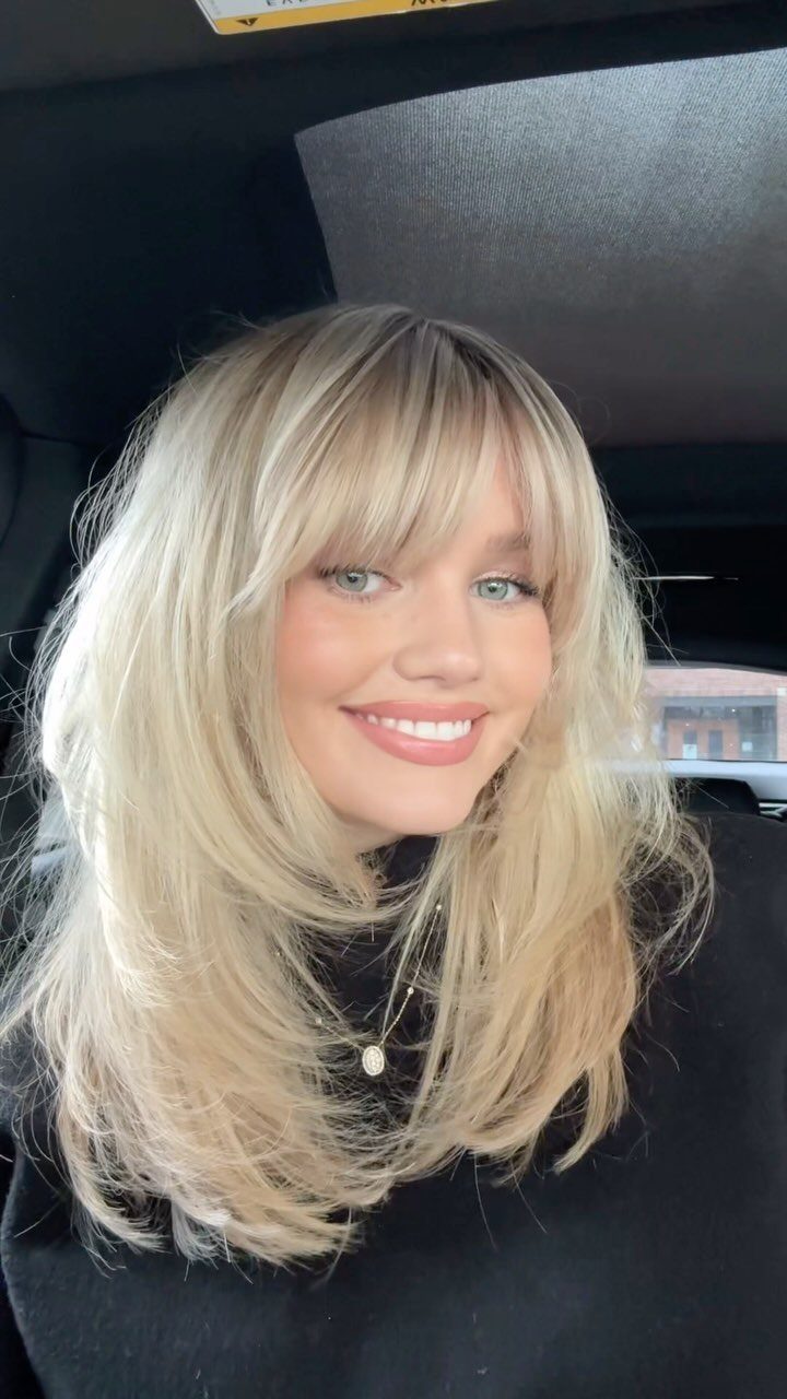 Woman with long blonde face-framing layers and soft bangs