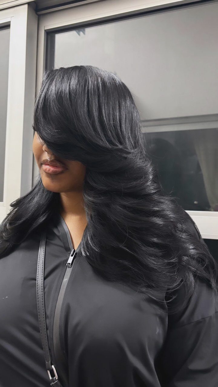 Long dark hair styled in soft, sweeping feathered layers