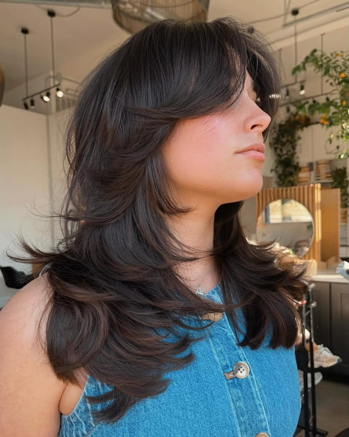 Woman with long dark hair styled in voluminous layers and tapered ends