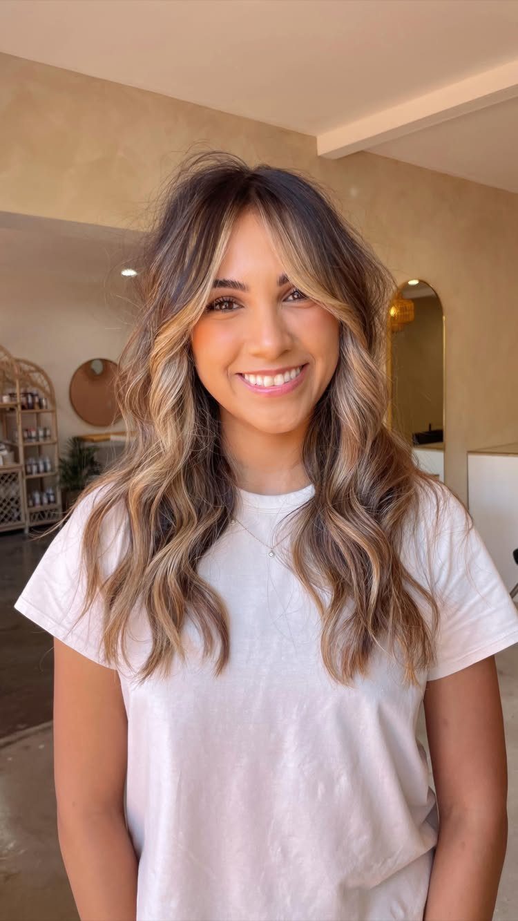 Woman with long wavy hair and highlighted face-framing pieces