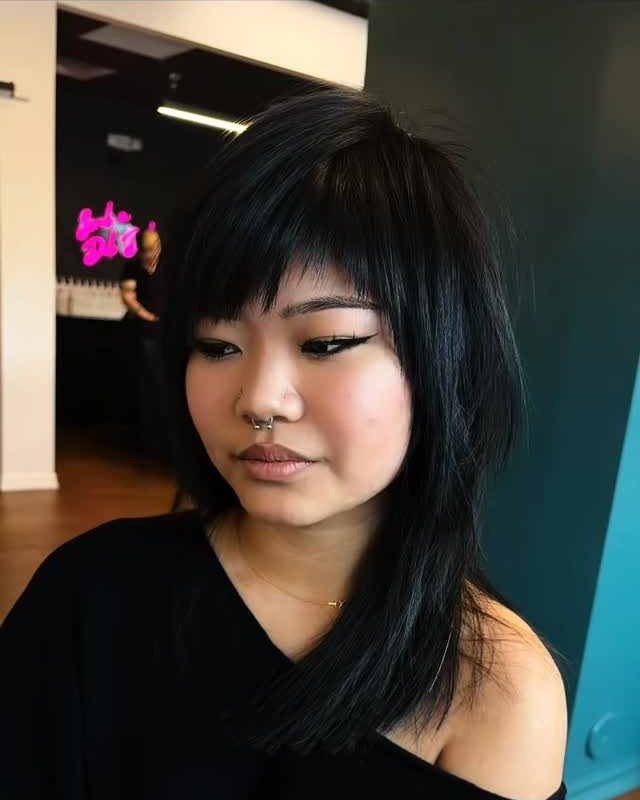 Person showing long black layered hair with a choppy, razored fringe