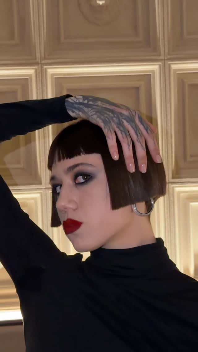 Short blunt bob with straight bangs framed by a boxy silhouette
