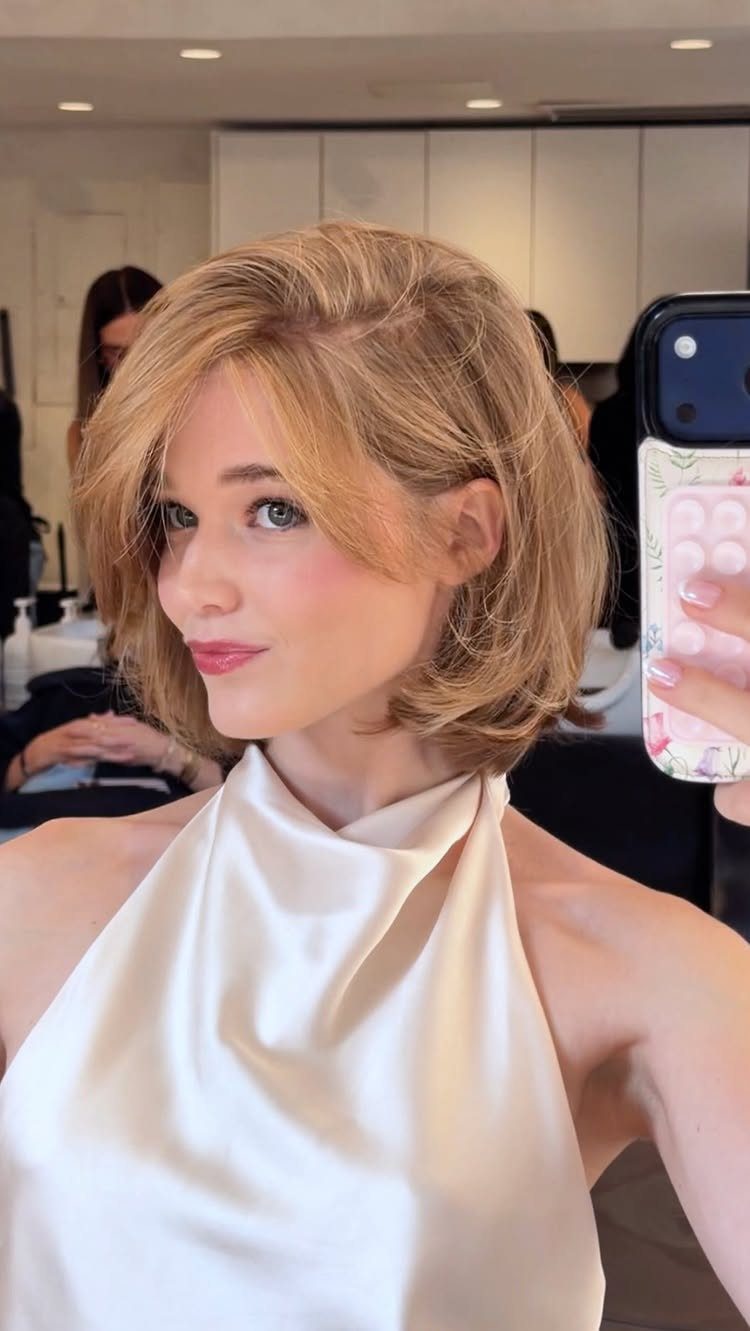 Woman showing short blonde butterfly bob with feathered face-framing layers