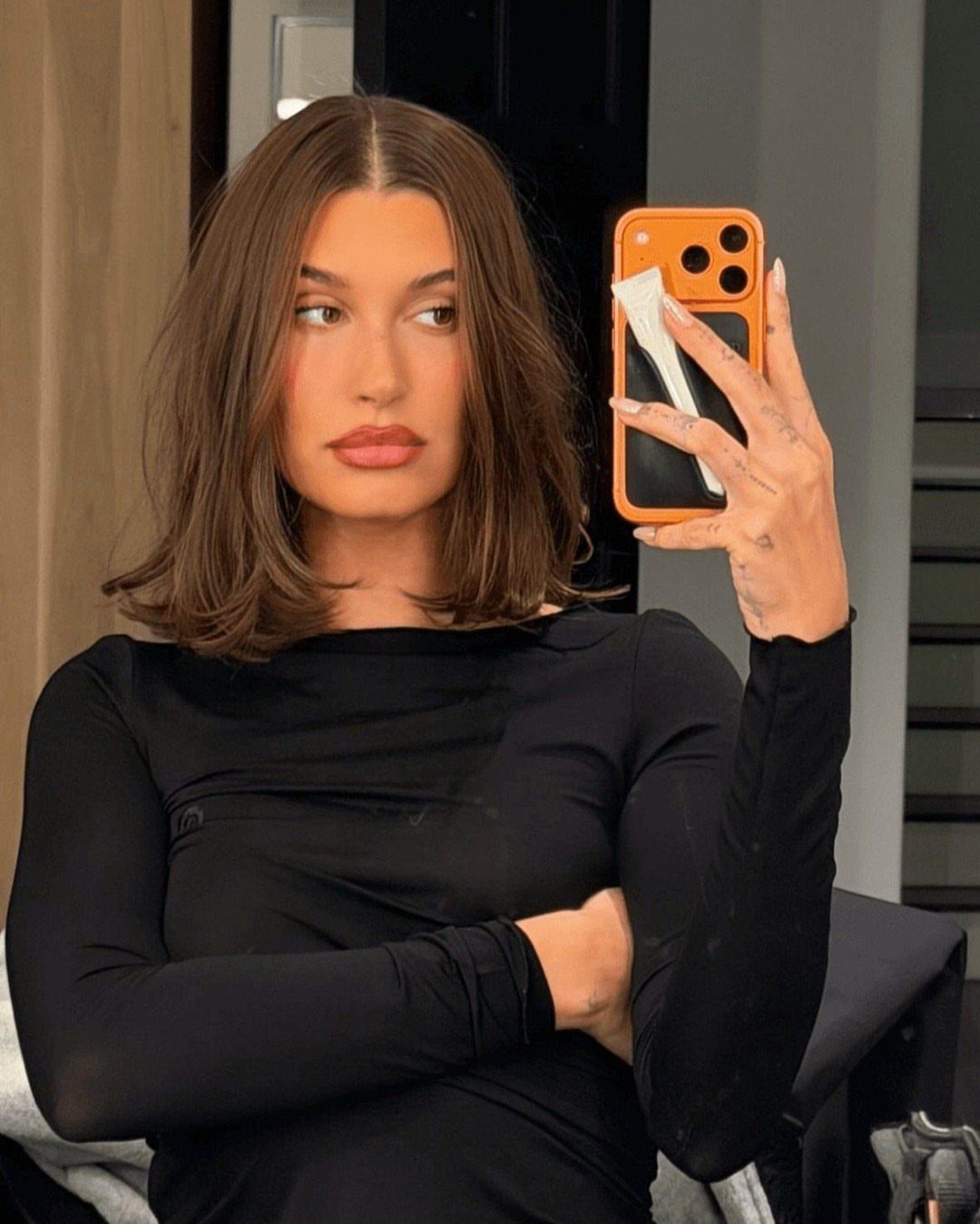 Woman with a center-parted brown bob taking a mirror selfie