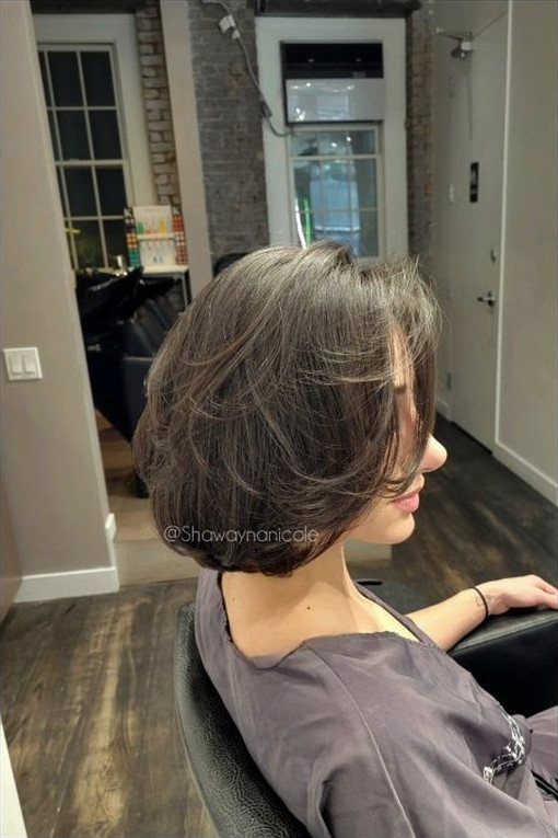 Woman in salon showing a voluminous, softly curved brown bob haircut
