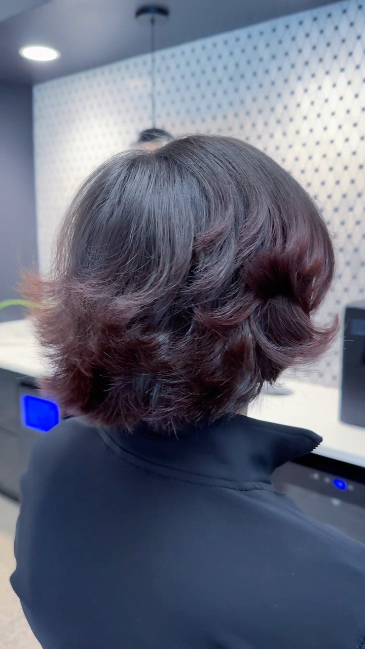 Layered dark bob with curled ends shown from behind in a salon
