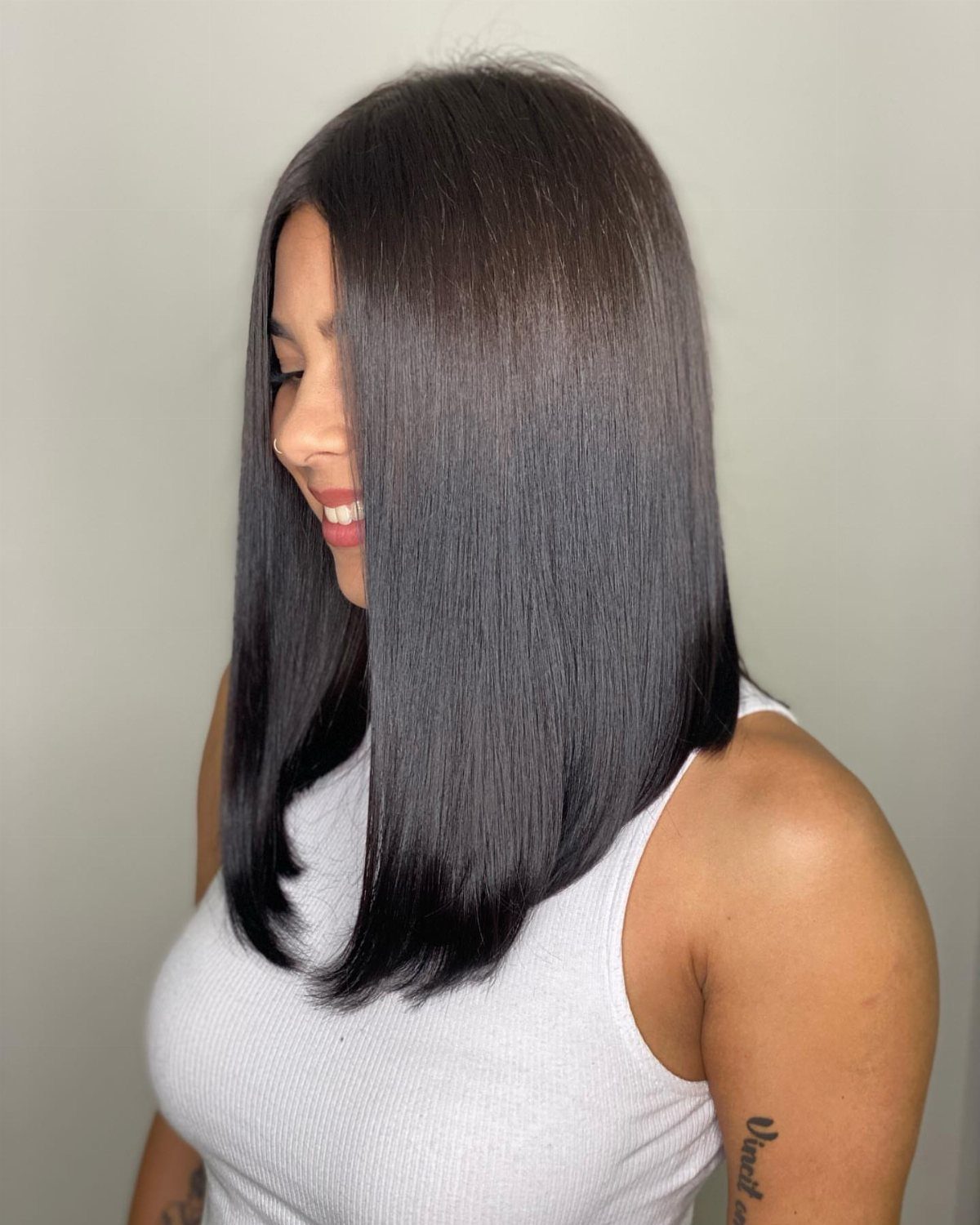 Woman showing a sleek, shoulder-length dark lob with softly curved ends