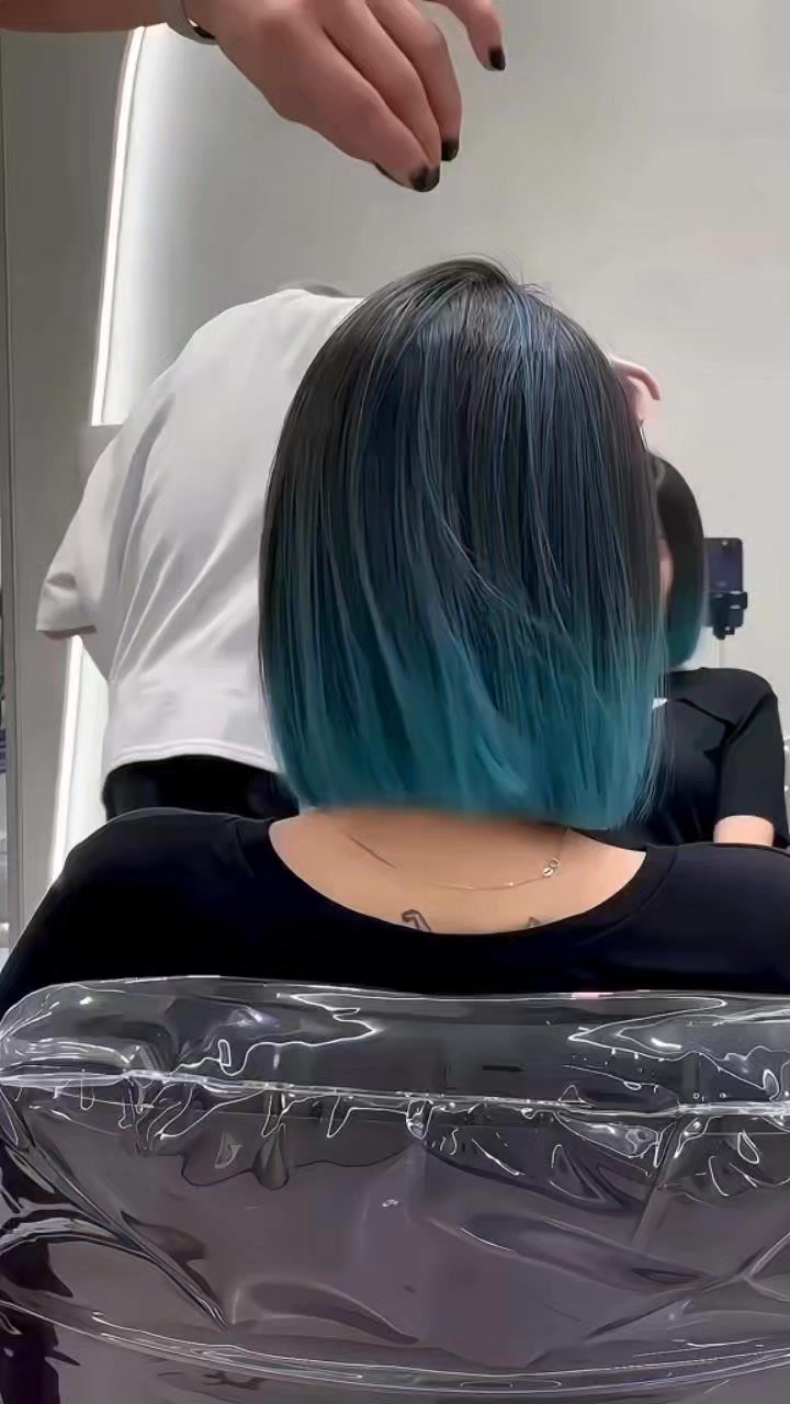 Teal-tipped bob haircut viewed from behind in a salon chair