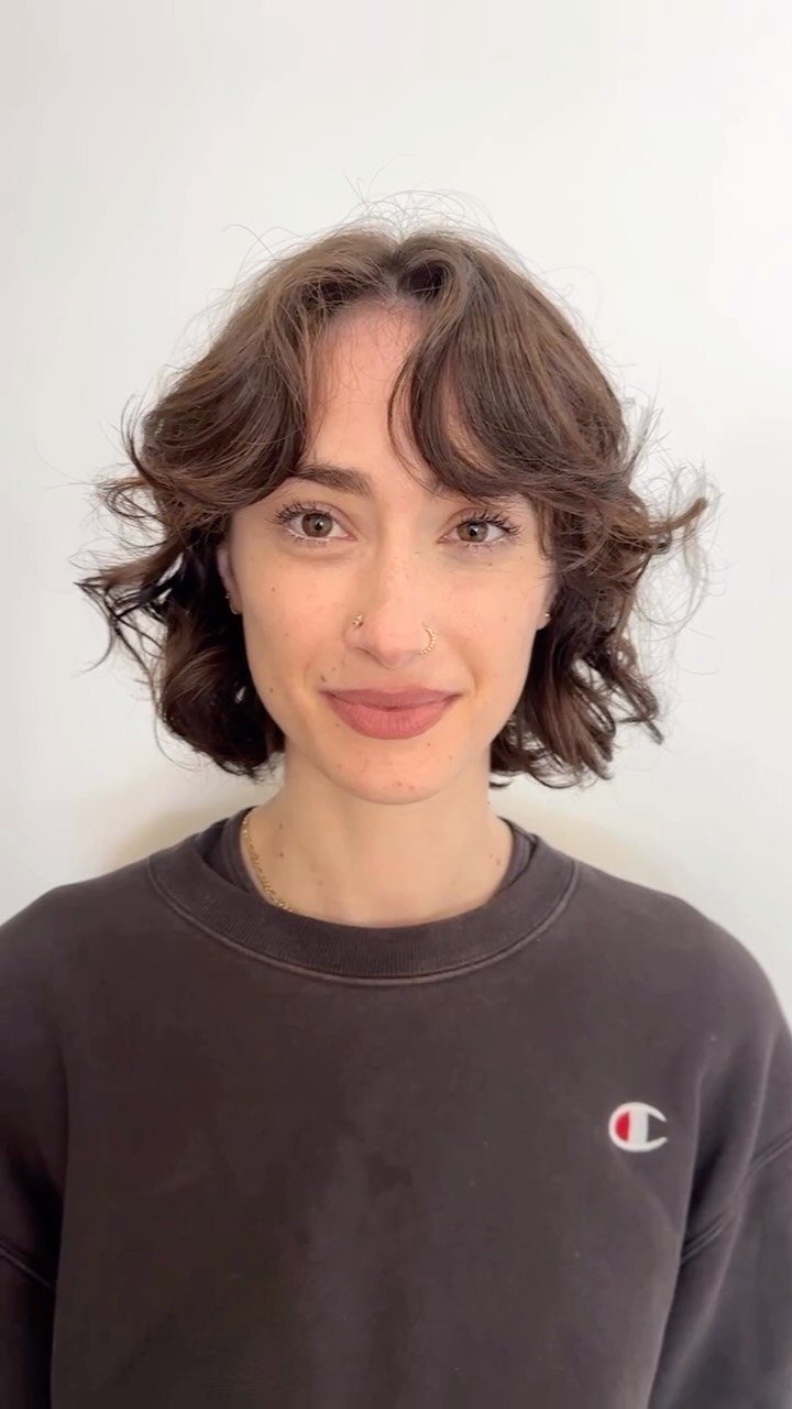 Person with a tousled, layered brown bob and curtain bangs
