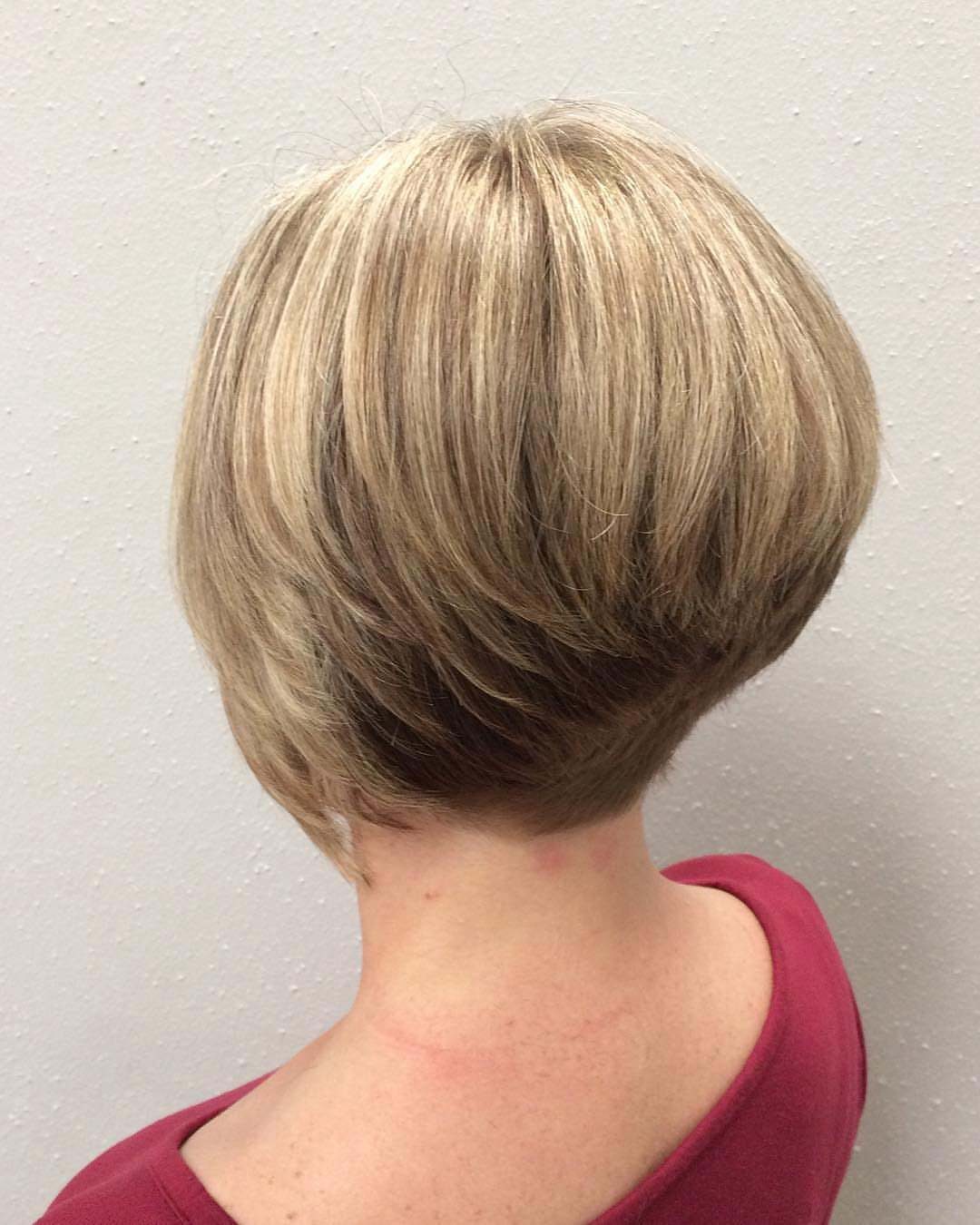 Short blonde wedge bob with golden highlights and tapered layers at the nape