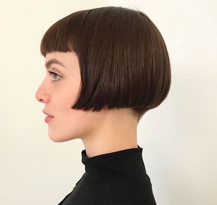 Dark brown bob haircut with blunt bangs shown in a clean side profile