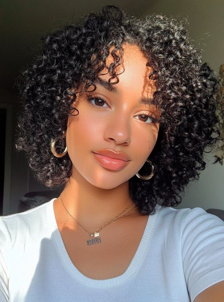 Woman showing a curly bob haircut with short bangs in sunlight