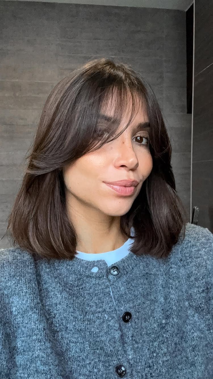 Woman with shoulder-length dark bob and parted curtain bangs sweeping away from her forehead