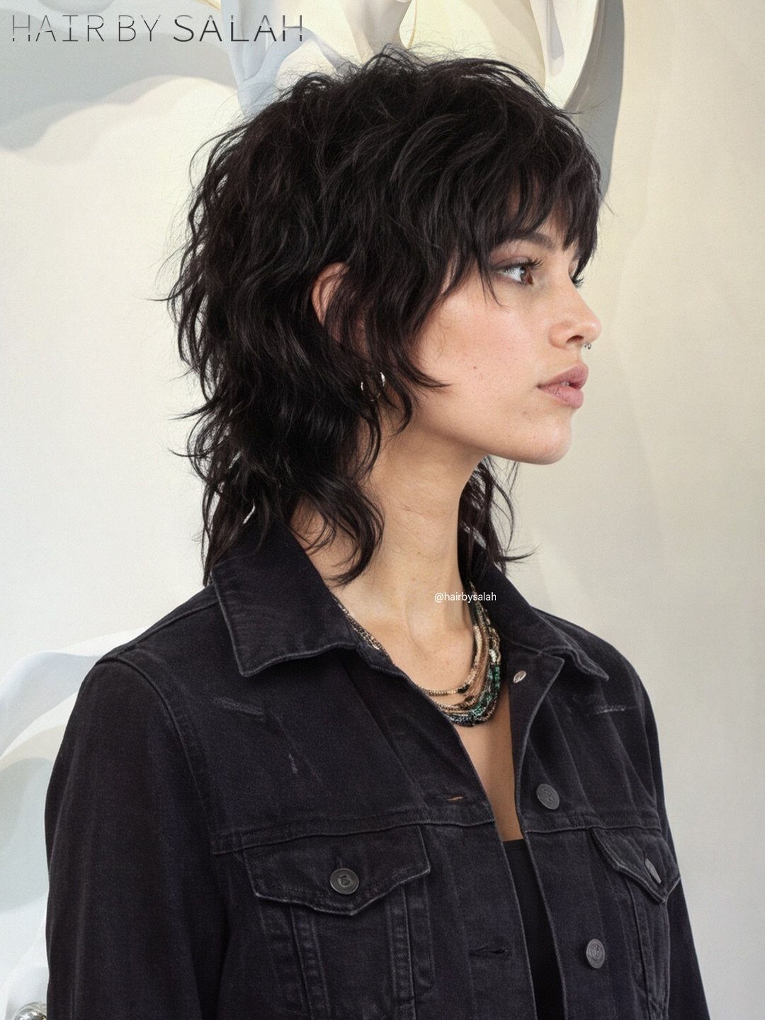 Woman with a dark shaggy bob, wavy layers, and short bangs