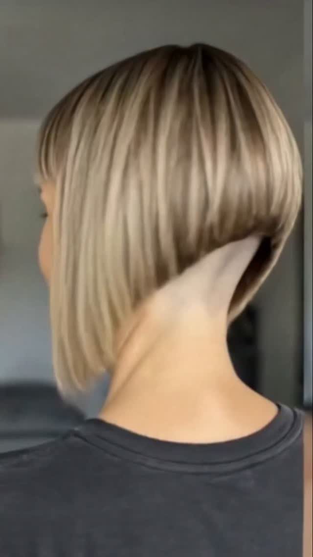 Blonde bob haircut with blunt bangs and dark roots, viewed from behind