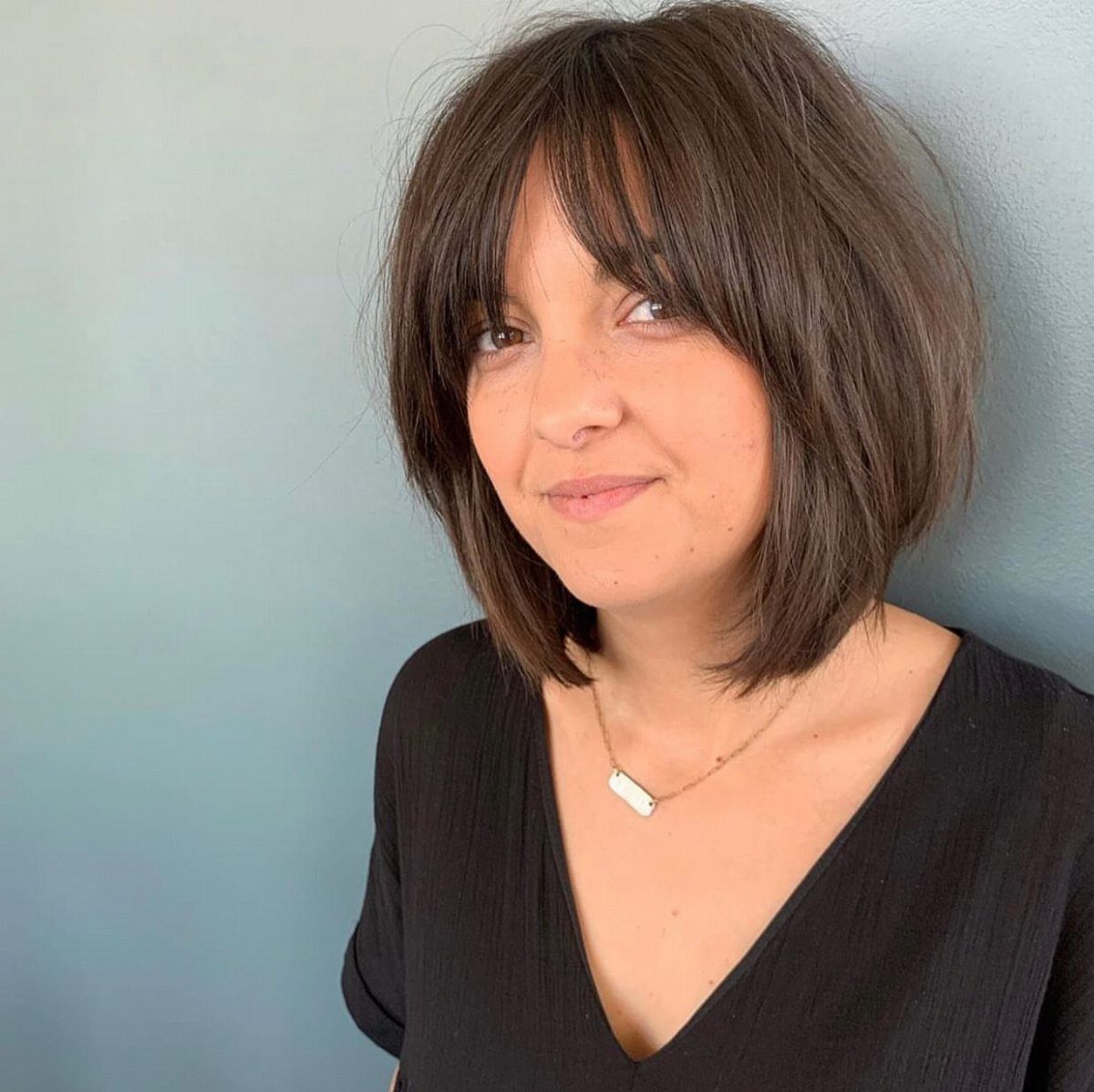 Woman with a chin-length dark bob and parted curtain bangs