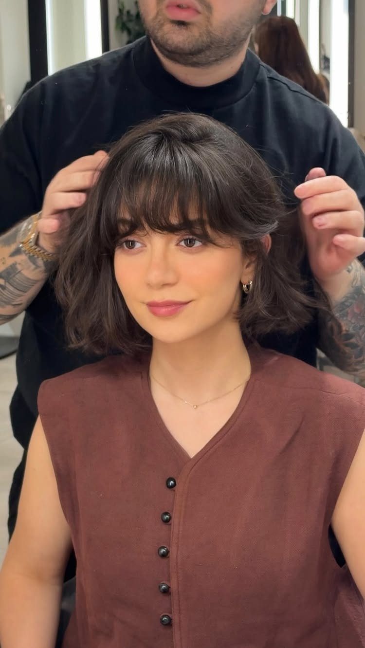 Woman with a chin-length layered bob and softly arched bangs in a salon