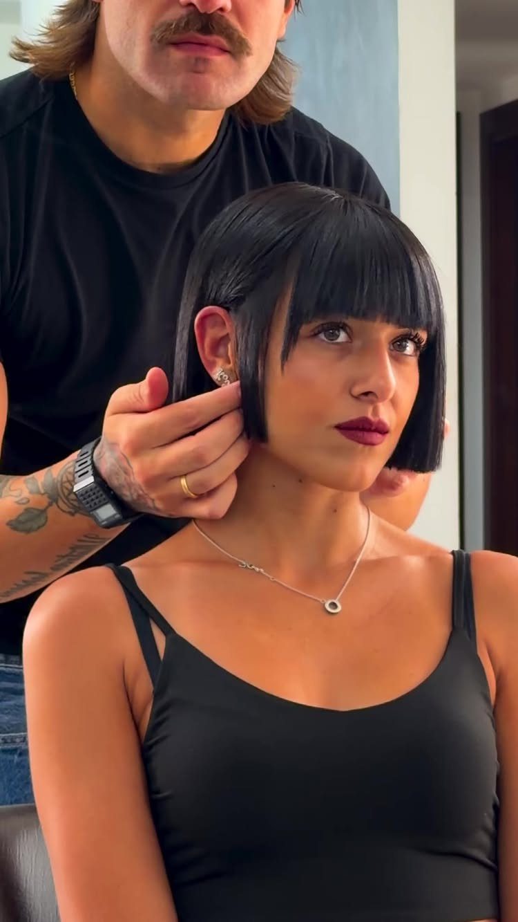 Woman in a salon with a blunt black bob and full eye-skimming bangs