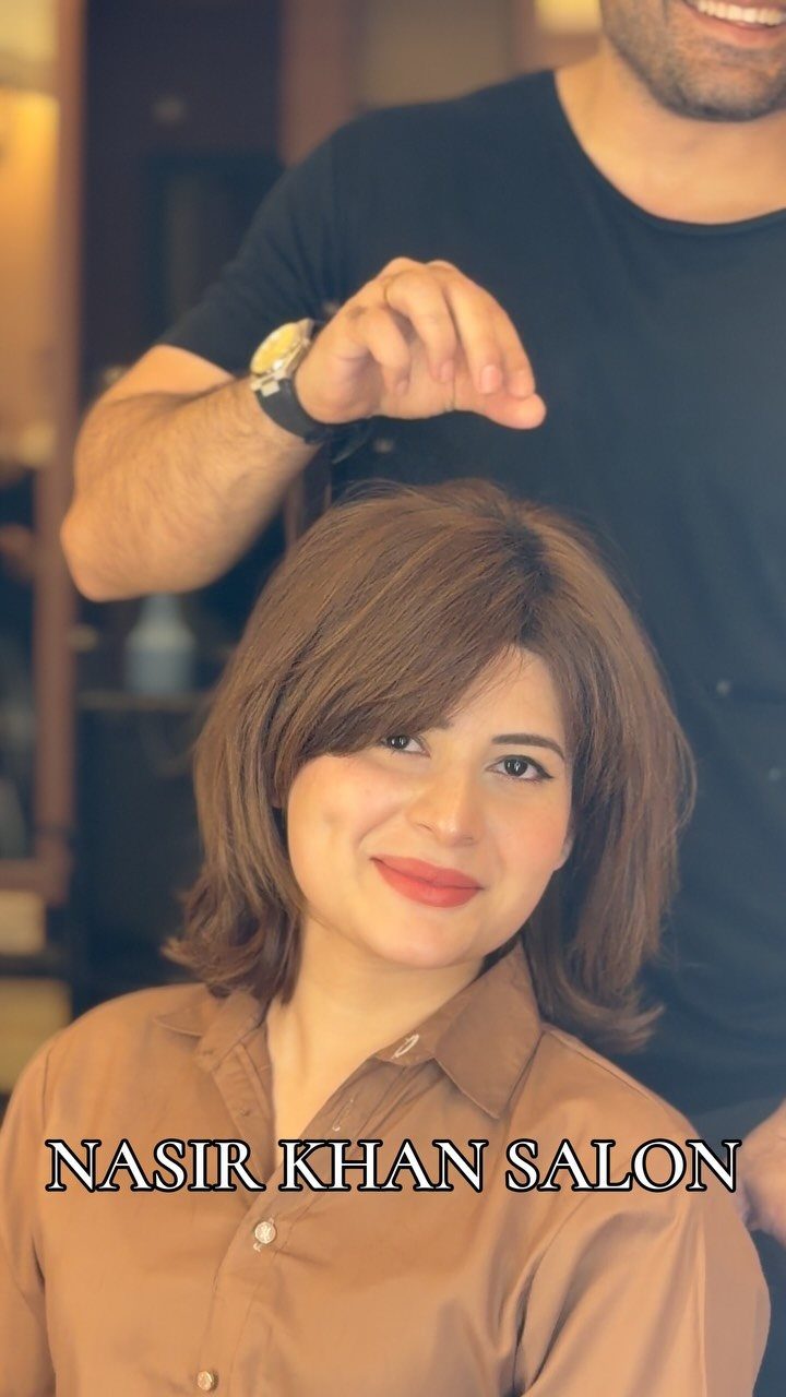 Woman displaying a layered brown bob with side-swept bangs in a salon chair