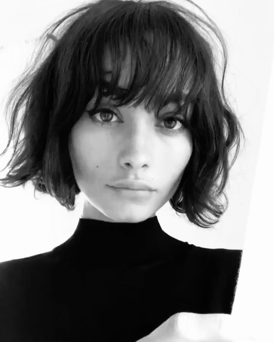 Person wearing a voluminous textured bob with sleek straight bangs in a black-and-white portrait