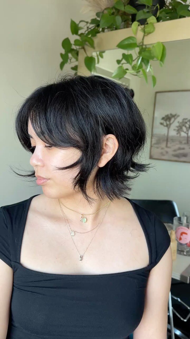 Layered black bob with feathered bangs and flipped textured ends