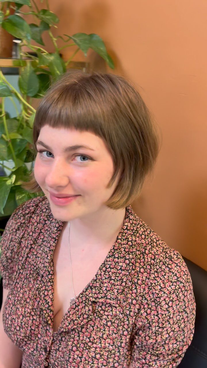 Short brown bob with very short straight bangs on a person posing