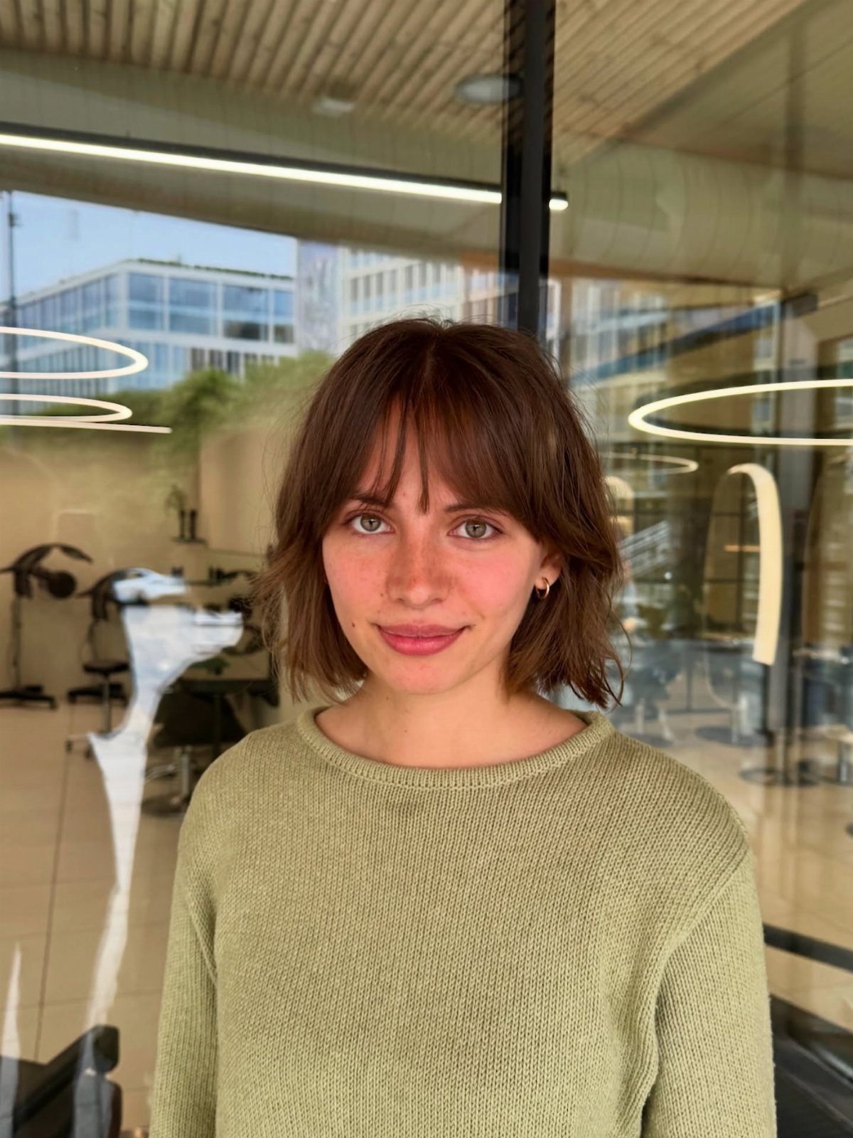 Woman with a short brown bob and piecey bangs in a knitted sweater