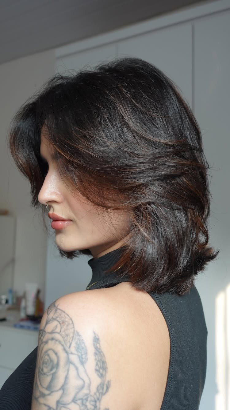Woman showing a dark shaggy bob with long side-swept bangs