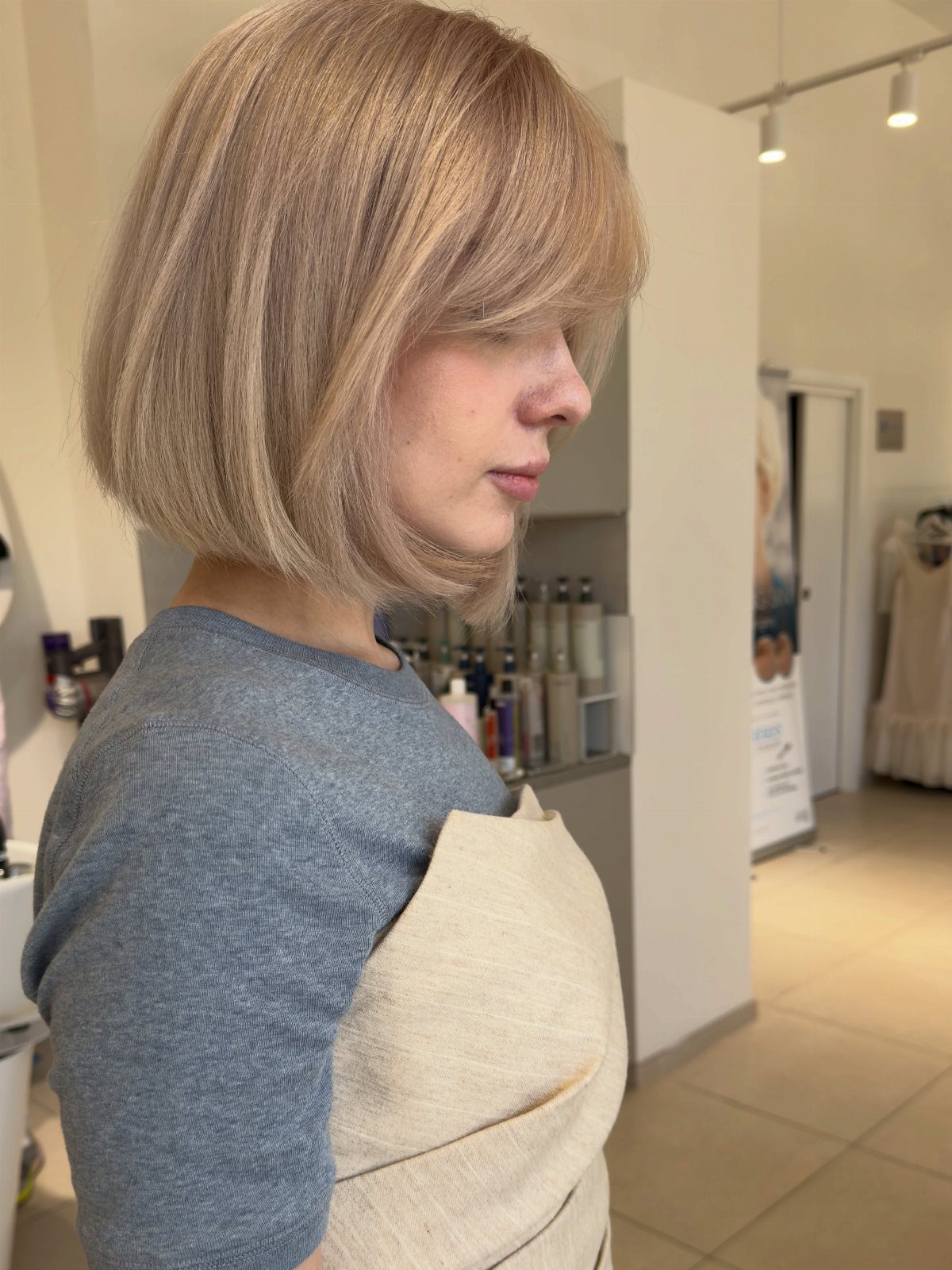 Woman displaying a smooth chin-length bob with sweeping bangs in a salon
