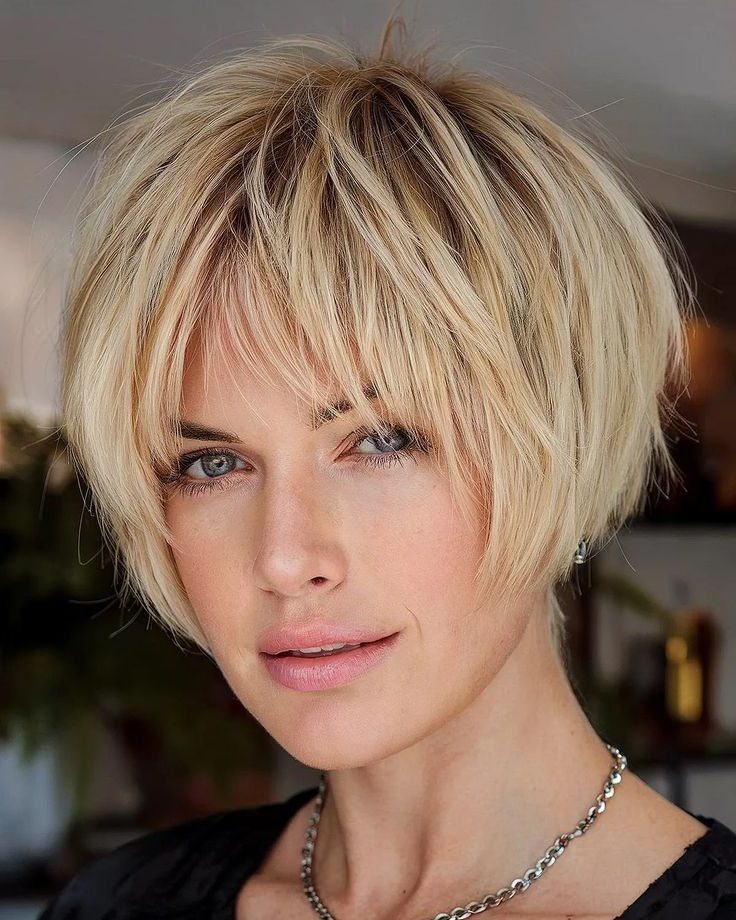 Woman with a short blonde bob and wispy bangs wearing a black top