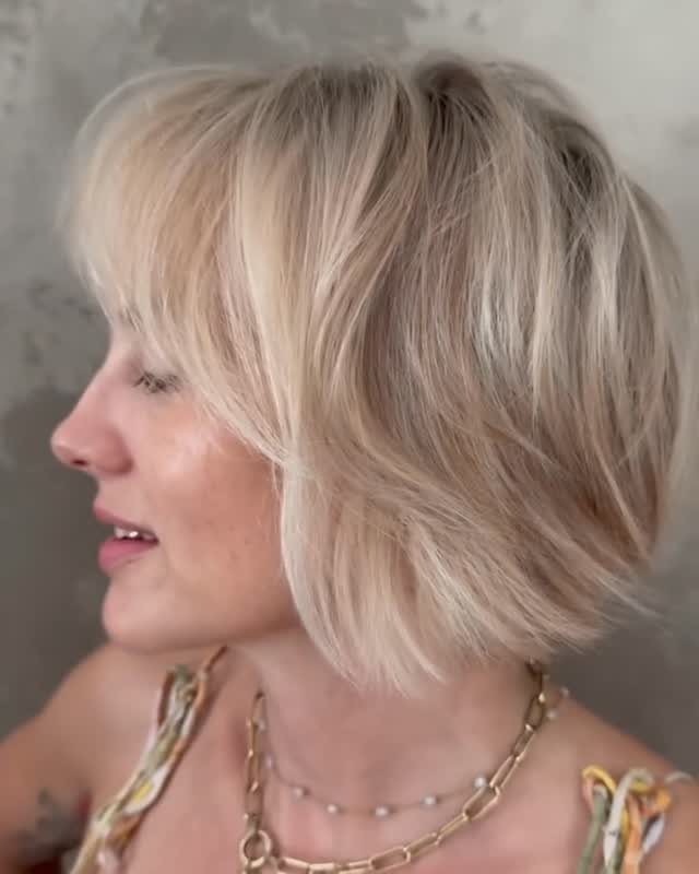 Woman with a jaw-length layered blonde bob and side-swept bangs