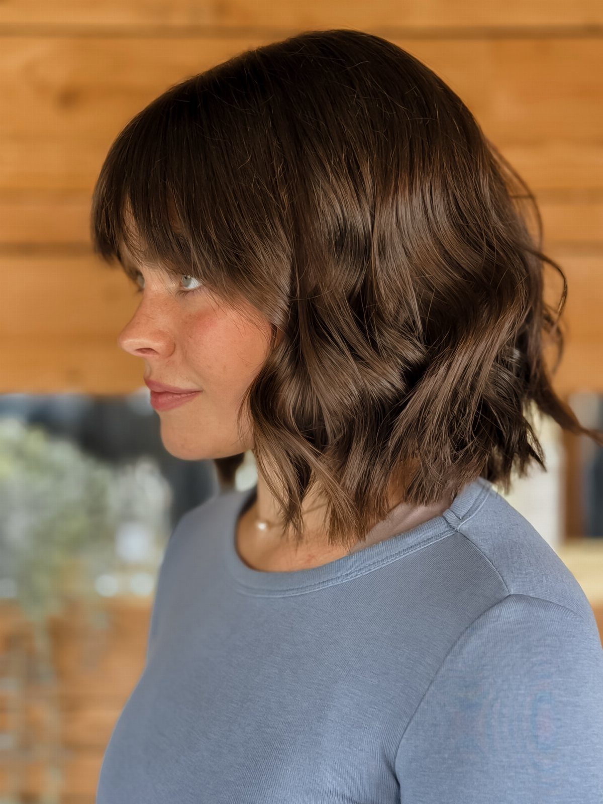 Woman with a tousled dark bob, loose waves, and long bangs