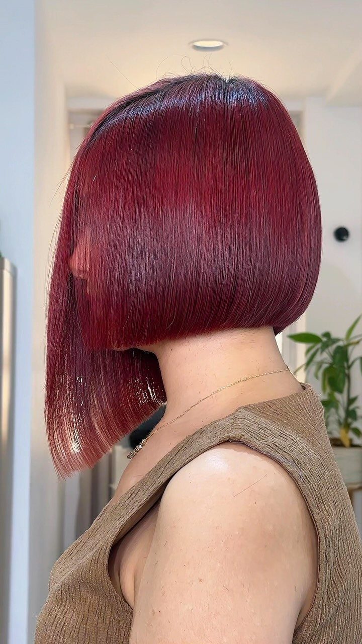 Burgundy asymmetrical bob with sleek glossy hair and visibly uneven side lengths