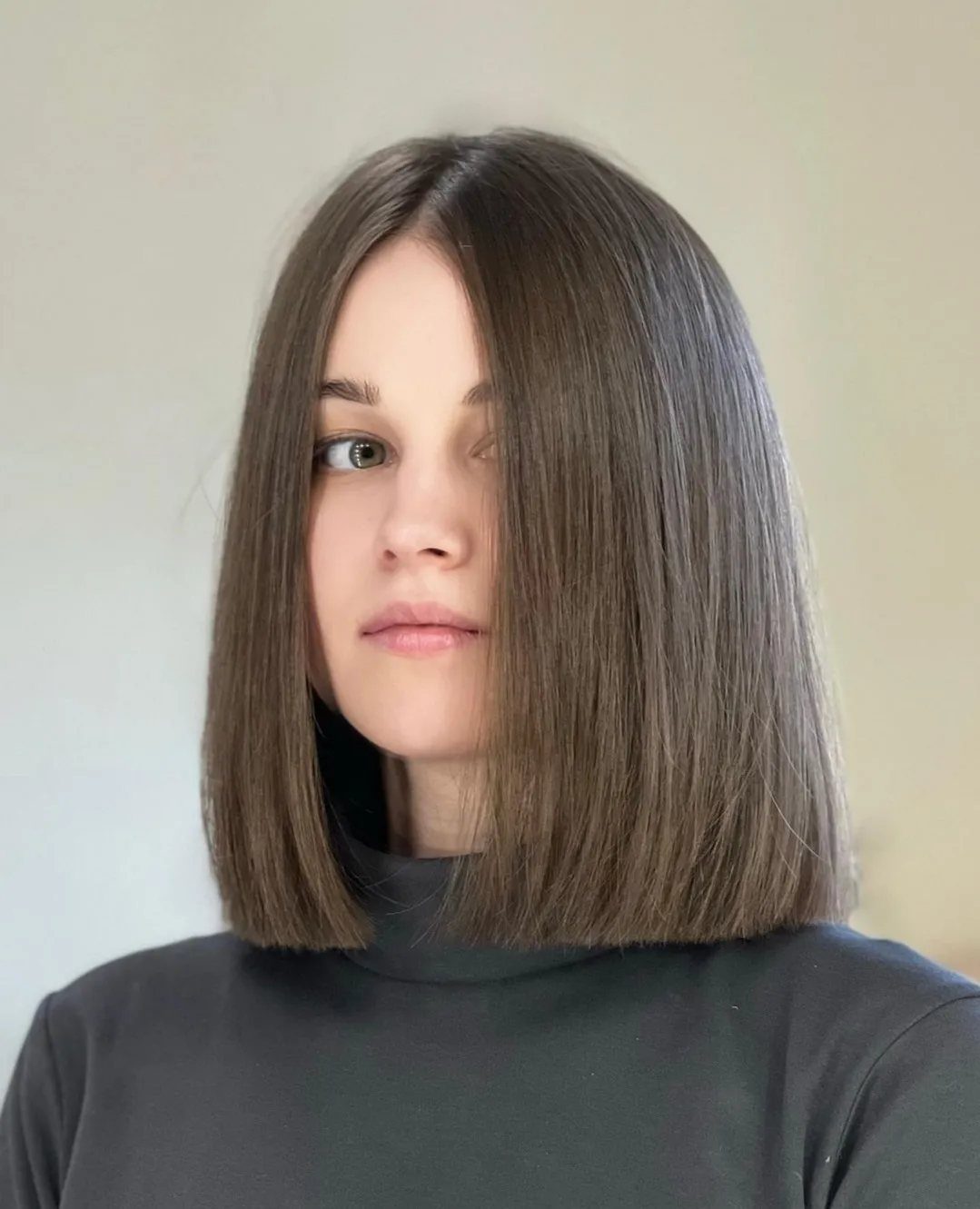Woman with straight dark brown hair in a blunt, shoulder-length bob