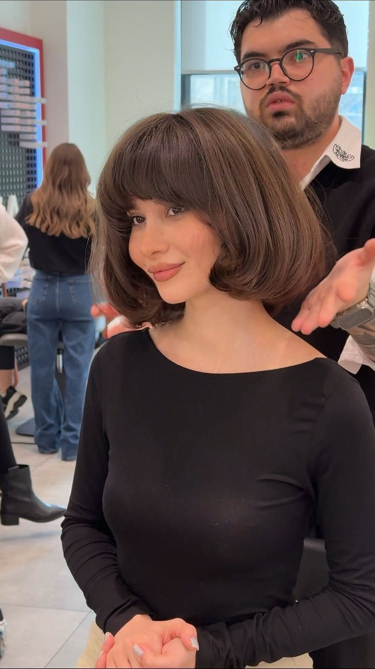Woman with a flared jaw-length brown bob and full bangs in a salon