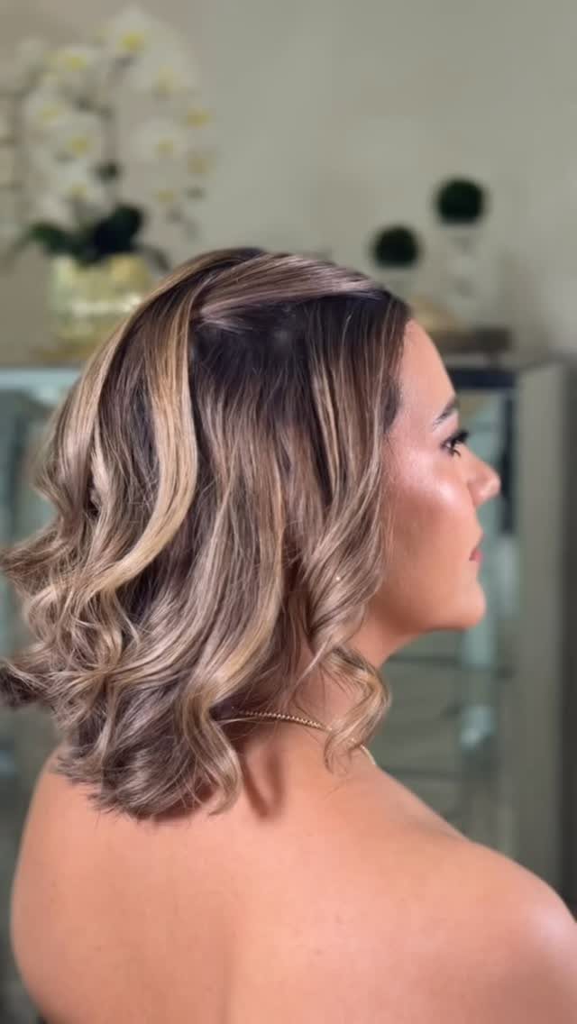 Woman showing a voluminous, highlighted side-parted wavy bob