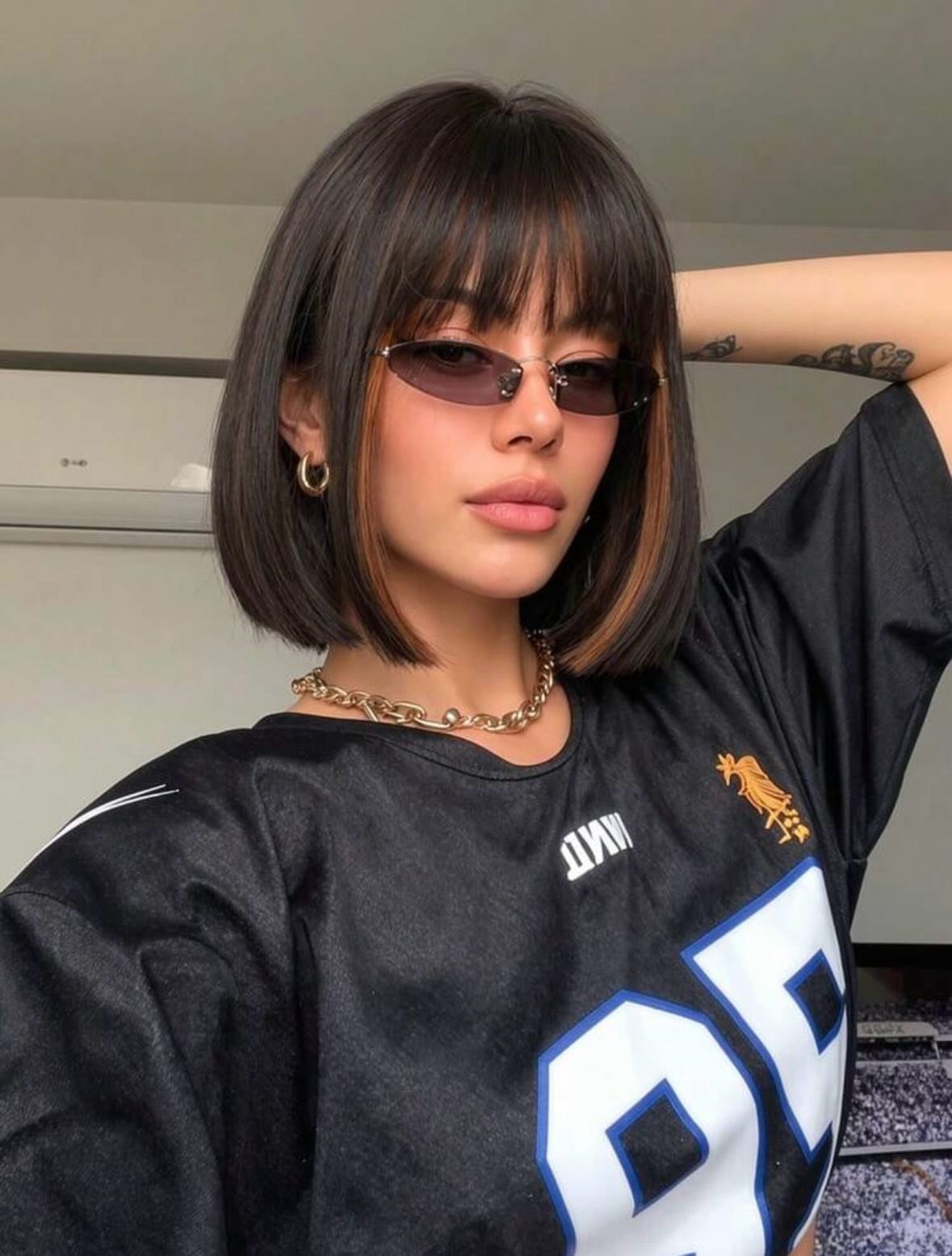 Person showing a neck-length dark bob with straight bangs and layered ends