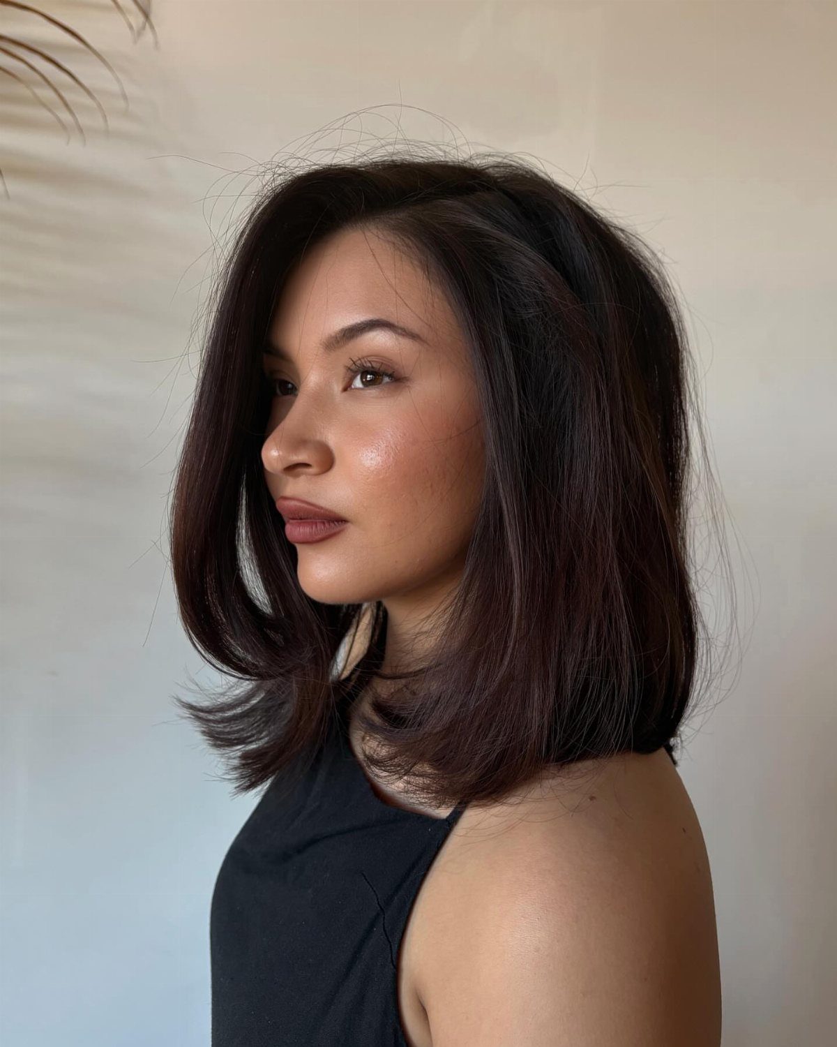 Woman with a side-parted dark long bob and curled-out flicked ends