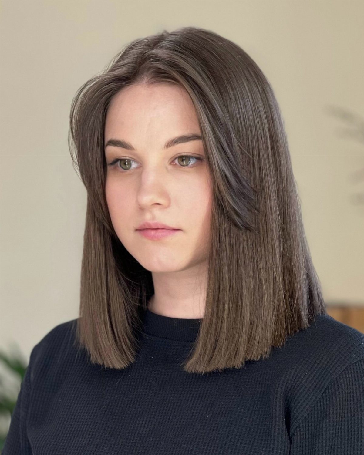 Woman with sleek, straight shoulder-length bob and a precise middle part