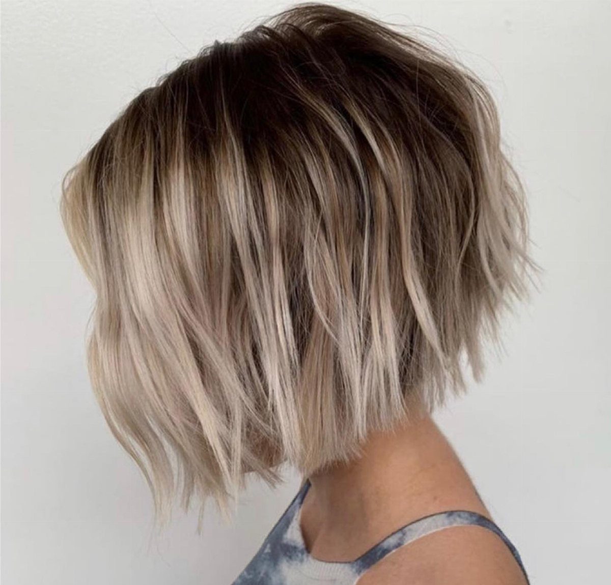 Wispy bob with dark shadow roots fading into platinum blonde ends