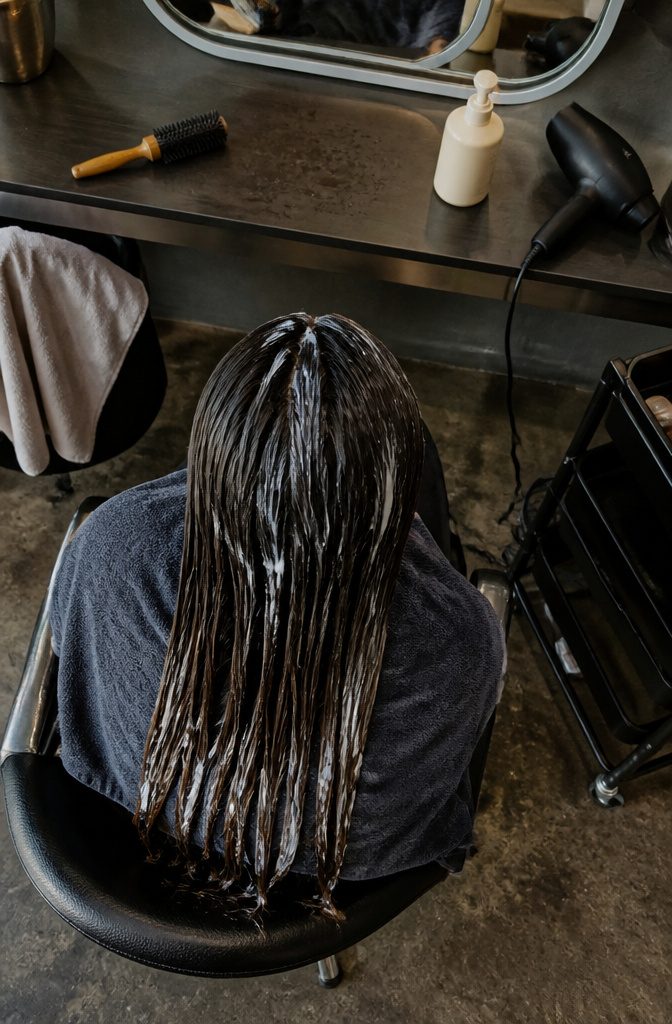 Styling mousse and root spray beside damp straight hair